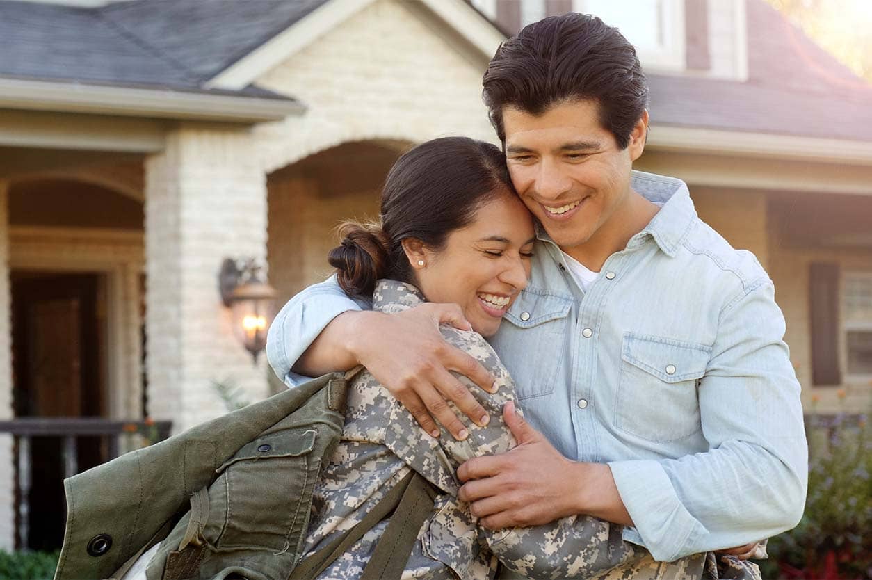 A couple hugging in front of their home