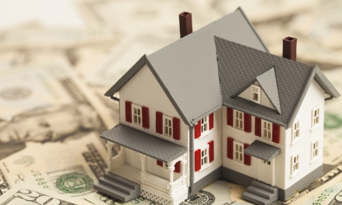 Model of a house sitting on top of a pile of money